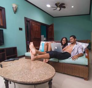 un hombre y una mujer acostados en un sofá con un portátil en Villa Dora Mae, en Ocho Ríos