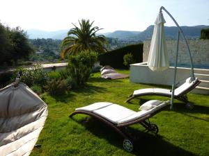 een paar stoelen en een paraplu in het gras bij Chambre d'hotes Casa Biba in Vence