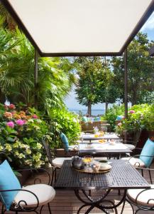 eine Terrasse mit Tischen, Stühlen und Blumen in der Unterkunft Park Hotel in Desenzano del Garda