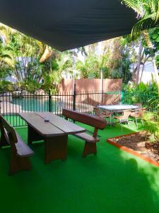 a patio with a table and benches on green grass at Mission Beach Retreat in Mission Beach