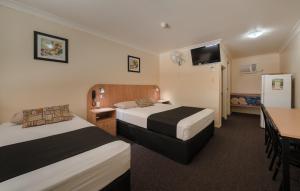 Habitación de hotel con 2 camas, mesa y cocina en Winter Sun Motel, en Rockhampton