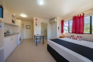 1 dormitorio con 1 cama, cocina y mesa en Winter Sun Motel en Rockhampton
