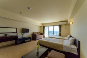 a hotel room with a bed and a television at Condominium Hotel Monpa in Chatan