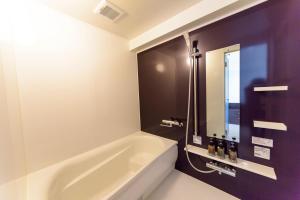 a bathroom with a white tub and a mirror at Condominium Hotel Monpa in Chatan
