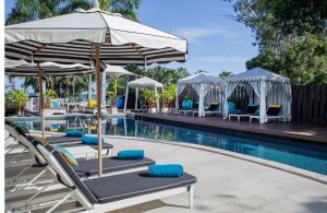 a pool with lounge chairs and umbrellas next to a swimming pool at Wave Hotel Pattaya in Pattaya Central