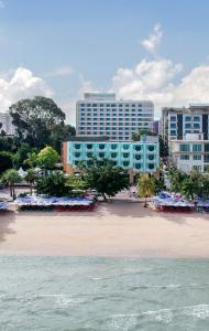 a beach with blue buildings and the ocean at Wave Hotel Pattaya in Pattaya
