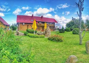 a house with a red roof and a yard at Pas Medžiotoją Motelis in Kryžkalnis