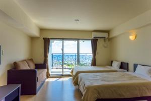 a hotel room with two beds and a large window at Condominium Hotel Monpa in Chatan