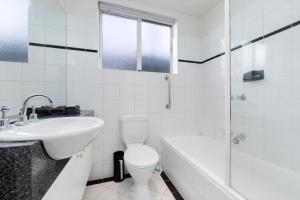 a white bathroom with a toilet and a sink at StayCentral - Brunswick Vibe Parkville in Melbourne