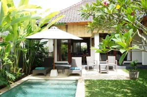 a villa with a swimming pool and an umbrella at Villa Mangga in Ubud