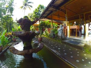 a fountain in the middle of a pond in a garden at Pondok Batur Indah Homestay Karangasem in Tirtagangga