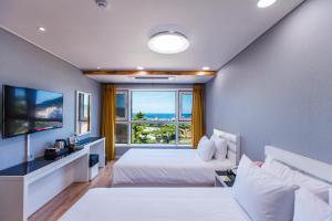 ein Schlafzimmer mit einem Bett und einem großen Fenster in der Unterkunft Hotel Sweet Castle Jeju Hamdeok in Jeju-do