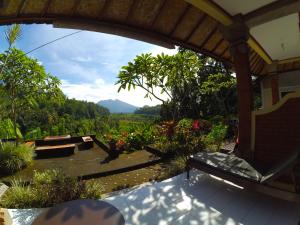 Pondok Batur Indah Homestay Karangasem في Tirtagangga: شرفة مع مقعد وإطلالة على حديقة