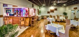 a restaurant with white tables and chairs and a bar at Tanoa Rakiraki Hotel in Rakiraki