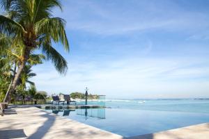 a swimming pool with palm trees and the ocean at Les 2 canons in Flic-en-Flac