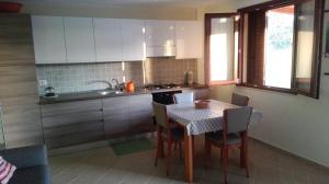 una cucina con tavolo e sedie e una cucina con armadietti bianchi di Bilocale vista mare a Costa Rei