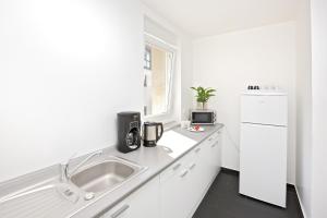 eine weiße Küche mit einer Spüle und einem Kühlschrank in der Unterkunft Pension Arkade Heilbronn in Heilbronn