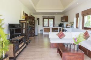 a living room with a white couch and a tv at Tropical Season Villa Resort in Mae Nam