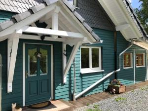 ein blaues Haus mit grüner Tür und Markise in der Unterkunft Ferienhaus Momo in Nieder-Kinzig
