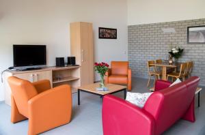 a living room with orange and red chairs and a table at Vakantiepark Broedershoek in Koudekerke