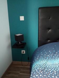 a bedroom with a bed with a black headboard and a blue wall at La Petite Maison in Ouches