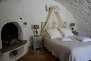 a bedroom with a white bed and a fireplace at La Vieille Bergerie in Èze