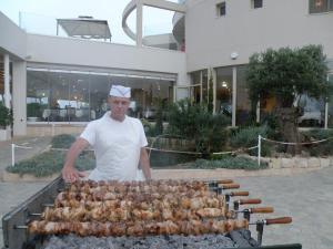 un hombre está cocinando pollos en una parrilla en Polyxenia Isaak Villa Heaven Pernera, en Protaras