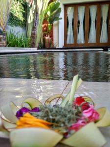 un tazón de flores sentado junto a una piscina en Jayastuti House, en Ubud