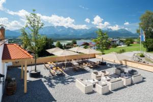 eine Terrasse mit Tischen, Stühlen und Sonnenschirmen in der Unterkunft Hartungs Hoteldorf in Füssen