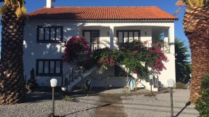 una casa blanca con flores delante en Home Pico - Casa dos Cedros (Alojamento local), en Criação Velha