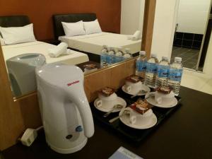 a kitchen with a mixer and cups and bottles of water at T-Hotel Ipoh in Ipoh