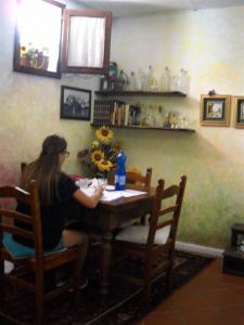 a woman sitting at a table in a room at B&B ANNA in Forlì