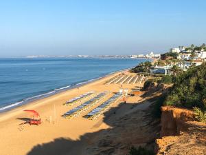 a beach with chairs and umbrellas and the ocean at Casa das Flores in Vale do Lobo