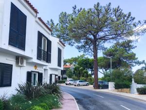 una calle con un árbol y un edificio blanco en Casa das Flores en Vale do Lobo