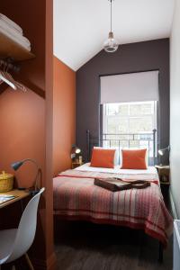 a bedroom with a bed with orange walls and a window at Peckham Rooms Hotel in London