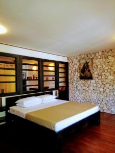 a bedroom with a large bed and a stone wall at Angelina Beach Resort & Italian Restaurant Malapascua in Malapascua Island