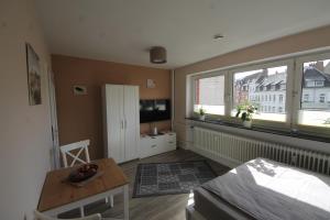 ein Wohnzimmer mit einem Tisch und 2 Fenstern in der Unterkunft Apartment am Blücherplatz in Kiel