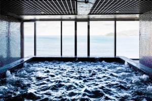a bath tub filled with water in a room with windows at Alana Nha Trang Beach Hotel in Nha Trang