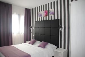ein Schlafzimmer mit einem großen weißen Bett mit lila Kissen in der Unterkunft Auberge de l'Etoile in Thoiry