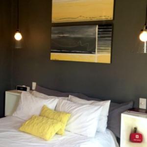 una camera da letto con un letto con lenzuola bianche e cuscini gialli di Annis Nest a Riebeek-Kasteel