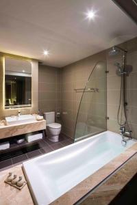 a bathroom with a tub and a toilet and a sink at Alana Nha Trang Beach Hotel in Nha Trang