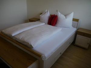 ein Bett mit weißer Bettwäsche und roten Kissen darauf in der Unterkunft Ferienhaus Sam in Innsbruck