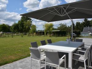 einen weißen Tisch und Stühle mit Sonnenschirm in der Unterkunft Modern villa in Rochefort close to the horses in Wavrielle