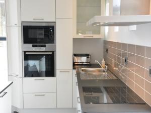 a white kitchen with a sink and a microwave at Modern Holiday Home in Fernelmont with Garden in Forville