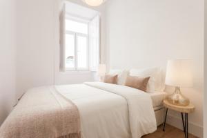 ein weißes Schlafzimmer mit einem weißen Bett und einem Fenster in der Unterkunft Your Lisbon Home Santa Apolonia in Lissabon