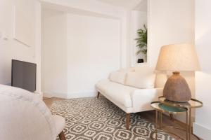 ein Wohnzimmer mit einem weißen Sofa und einer Lampe in der Unterkunft Your Lisbon Home Santa Apolonia in Lissabon