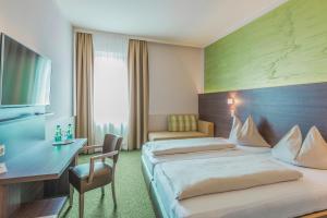 卡普芬贝格Sporthotel Kapfenberg的有两张床和一张书桌的酒店房间