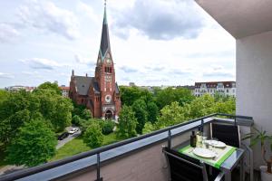 een balkon met uitzicht op een kerk met een klokkentoren bij Art'Appart Suiten - kontaktloser Check-In in Berlijn