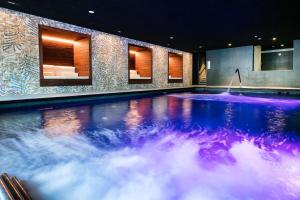 a large swimming pool with a blue and purple water at AQUA Hotel Silhouette & Spa - Adults Only in Malgrat de Mar