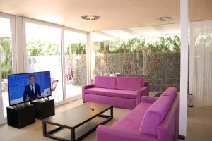 マスパロマスにあるeó Maspalomas Villaのリビングルーム(紫色のソファ、テレビ付)